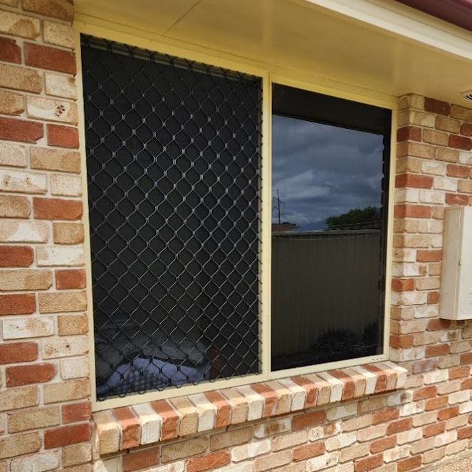 Black diamond grille security screen fitted to a window on a red brick house
