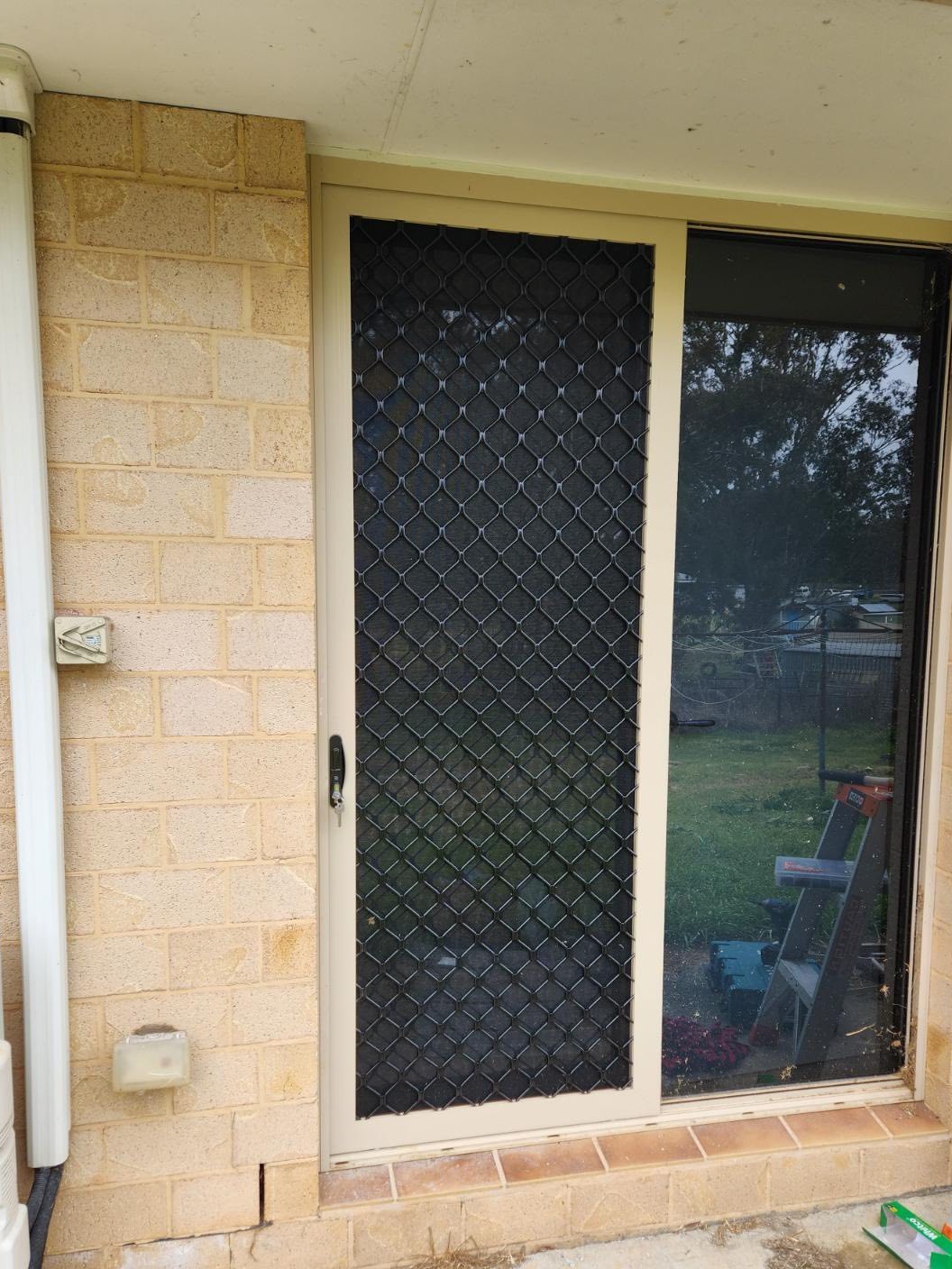 New diamond grille sliding security door installed on a besser block house