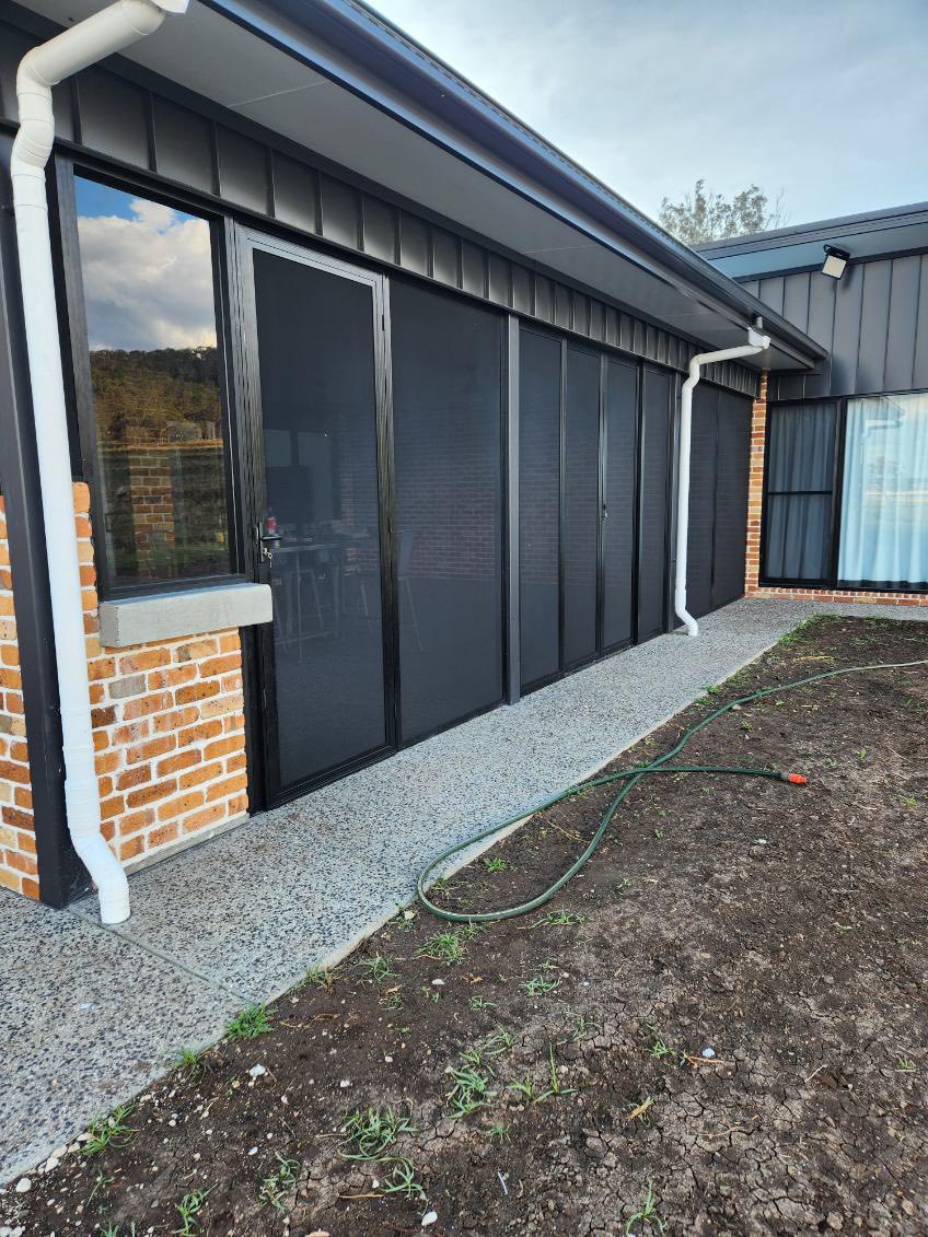 Long run of black security screens down the side of a modern dark clad house